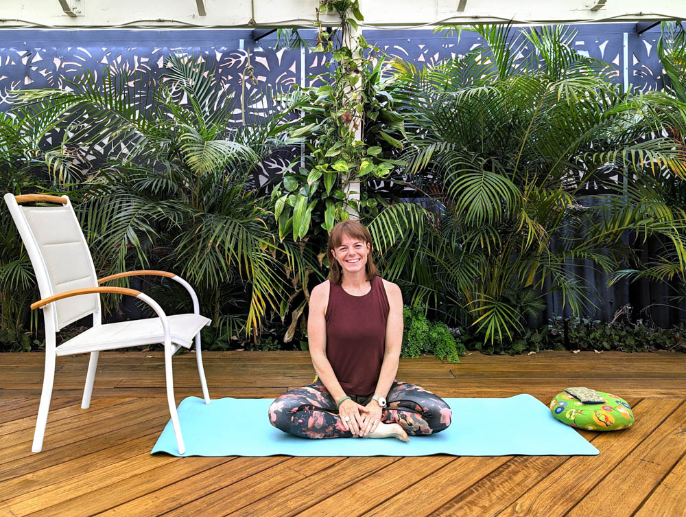 Heather seated on a yoga mat in a garden therapy setting