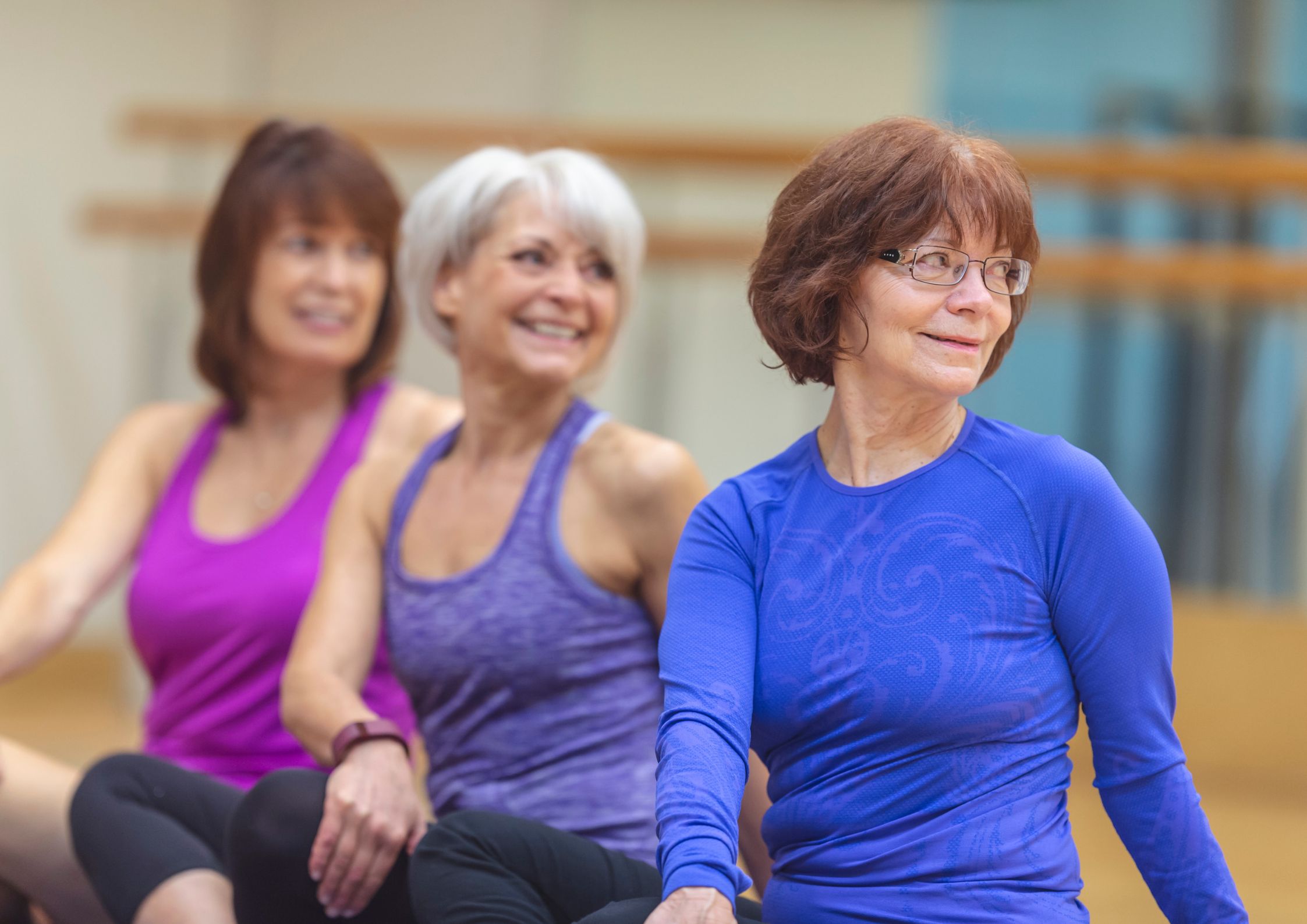 Three older students smiling together during a yoga class