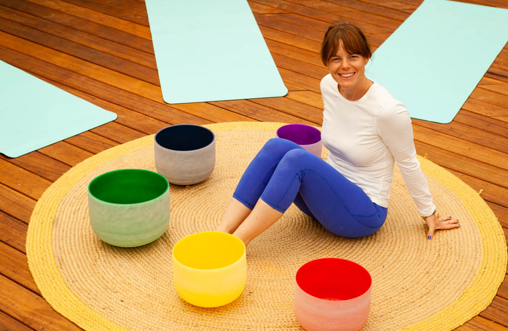 Heather smiling while seated among colourful singing bowls
