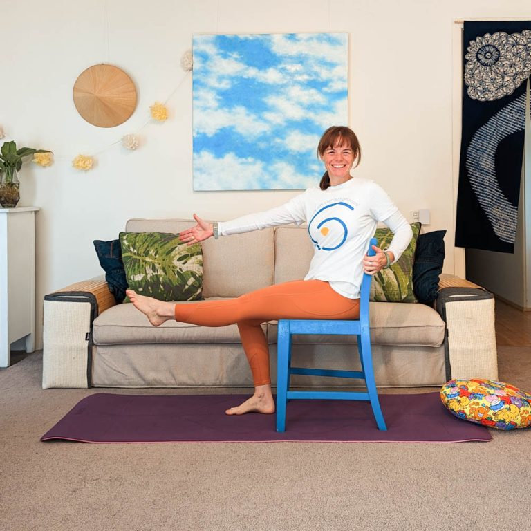 Heather smiling while demonstrating an accessible seated yoga movement
